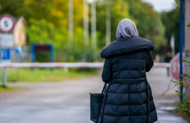 Woman walks on road, viewer sees her from behind